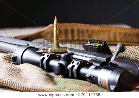 The Ammo With Black Bolt Action Rifle And Scope On The Multicam Background. Close Up.