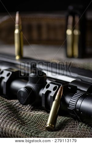 The Ammo With Black Bolt Action Rifle And Scope On The Multicam Background. Close Up.