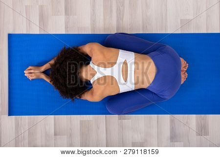 Athletic Woman Doing Yoga On Blue Fitness Mat Over The Hardwood Wood Floor