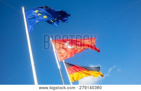 German, European Union, Turkey waving flags on white poles. Looking for friendship and co-operation. Blue sky background.