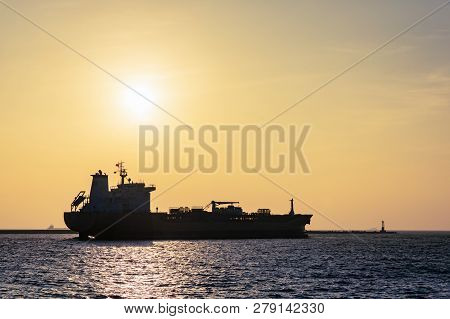 Large Cargo Ship Leaving Port As Sun Sets Through Smoggy Air
