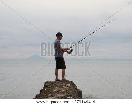 Anyer, Indonesia - June 25, 2018: A Man Arranged His Fishing Line On The Edge Of The Sea.