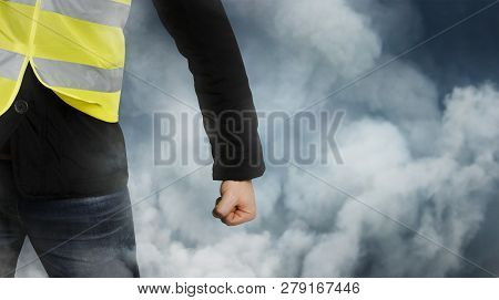 Yellow Vests Protests. Unrecognizable Man Clenched His Fist In Protest In Haze. The Concept Of Revol