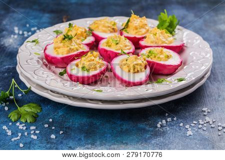 Beet-dyed Deviled Eggs. Easter Stuffed Eggs On Blue Background. Copy Space