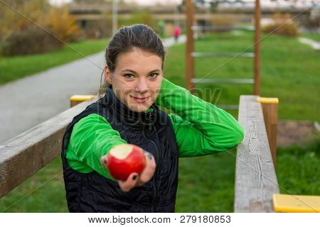 Fitnes Trainer Offering An Apple At Outdoor Gym.