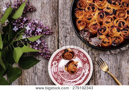 Homemade Mini Cherry Rolls In A Baking Form And Two Rolls On A Plate With Bouquet Of Lilac On Vintag