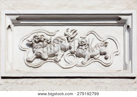 Ancient granite statue of mythological Chinese creatures Qilin on a old style brick and concrete wall,Fuzhou,Fujian,China