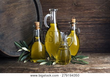Bottles Of Extra Virgin Healthy Olive Oil With Barrel Background