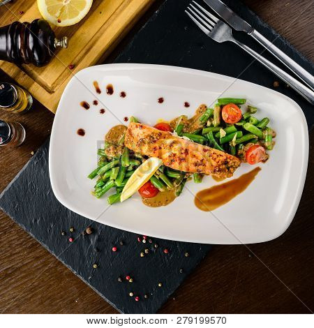 One Piece Of Baked Grillen Salmon Filet Pepper Lemon And Salt, With Vegetables Served On Black Stone