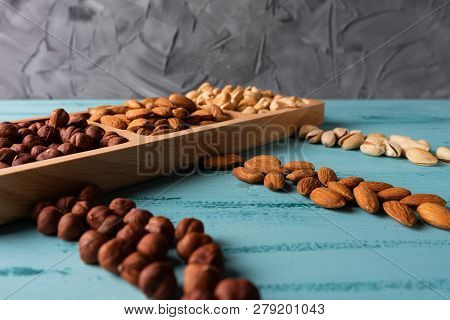 Compartmental Dish With Nuts On Blue Wooden Table. Cashew, Hazelnut, Almond.
