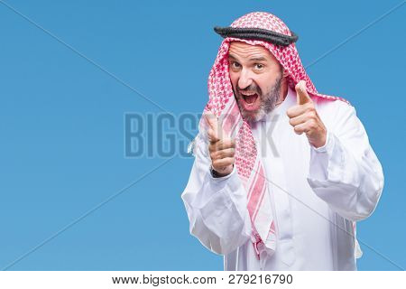 Senior arab man wearing keffiyeh over isolated background pointing fingers to camera with happy and funny face. Good energy and vibes.