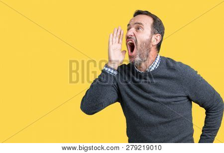 Handsome middle age senior man wearing a sweater over isolated background shouting and screaming loud to side with hand on mouth. Communication concept.