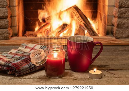 Mug Of Hot Tea, Wol Scarf And Candle Near Cozy Fireplace, In Country House, Winter Vacation.