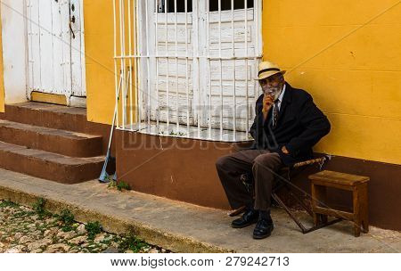 Trinidad, Cuba - 2019.street Portrait Of An Old Cuban Man, Who Is Sitting In Relaxation And Smoking