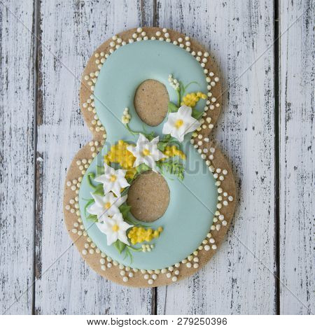 Cookie Covered With Glaze Made In A Form Of Number Eight With Sring Flowers On White Wooden Backgrou