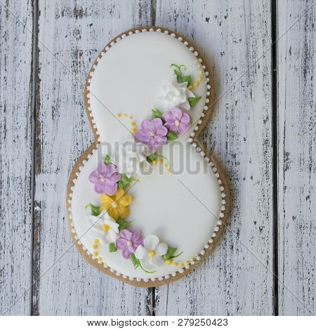 Cookie Covered With Glaze Made In A Form Of Number Eight With Sring Flowers On White Wooden Backgrou