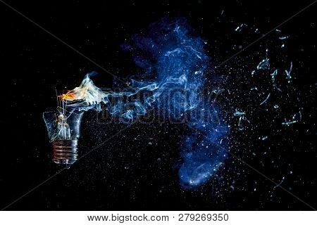 Cosmic Explosion Of A Burning Light Bulb With Flying Splinters And Smoke On A Black Background With