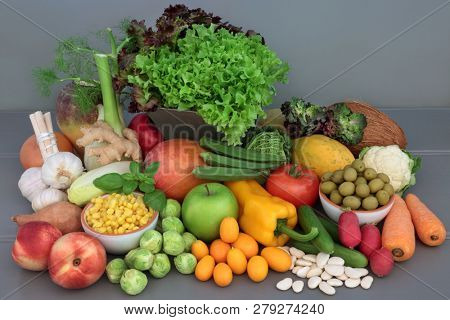Alkaline health food of fresh vegetables, fruit, herbs, spice and dried legumes on grey wood table background. High in antioxidants, anthocyanins, fibre, minerals and vitamins.  
