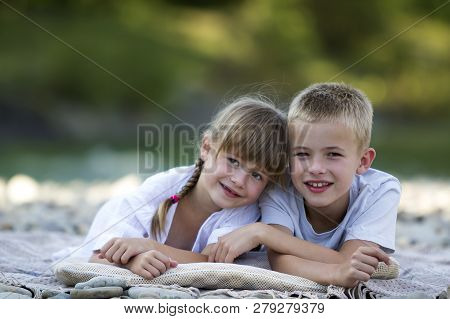 Two Young Happy Cute Blond Smiling Children, Boy And Girl, Brother And Sister Laying Embraced On Peb
