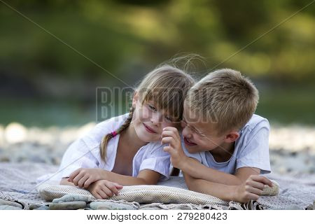 Two Young Happy Cute Blond Smiling Children, Boy And Girl, Brother And Sister Laying Embraced On Peb