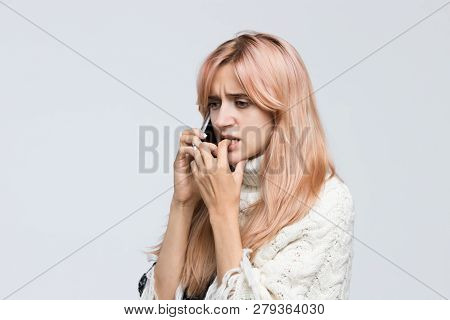 Studio Portrait Of Blonde Girl In White Sweater Talking On The Phone, Said Terrible News, Sad Look, 