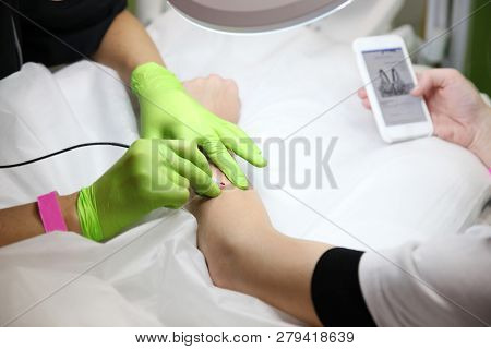 Girl During The Procedure To Remove Unwanted Hair On His Hand Looking At Your Phone