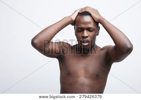 Desperate Black Young Man Keeps Both Hands On Head, Closes Eyes, Suffers From Migraine, Has Sad Fati