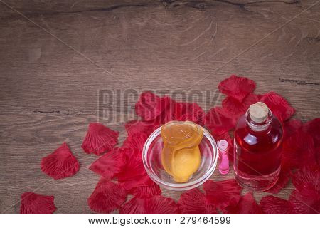 Perfumed Rose Water And Rose Flower Made Of Soap In Glassware On Wooden Table With Rose Petals. Back