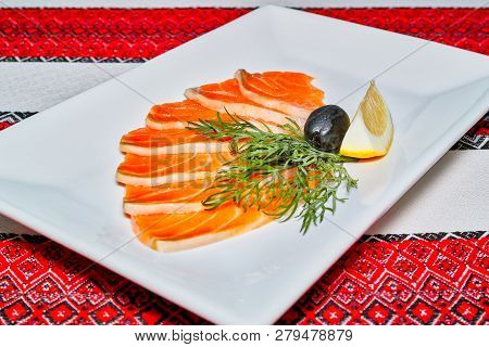 A Dish With Slices Of Salmon With A Slice Of Lemon And Olive.