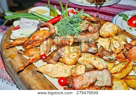 Wooden Board With Grilled Meats And Baked Potatoes With Dill.