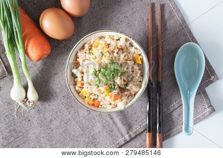 Bowl Of Fried Rice, Carrot And Egg On Pink Fabric, Spoon, Chopsticks And Ingredients For Background