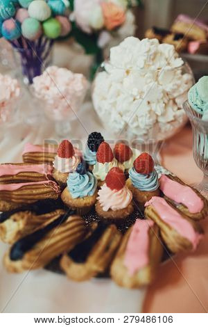 Delicious Colorful Cupcakes And Eclairs On The Wedding Candy Bar