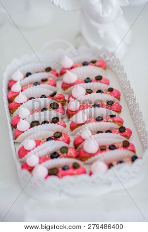 Eclairs Covered With Pink Glaze And Decorated With Blackberries