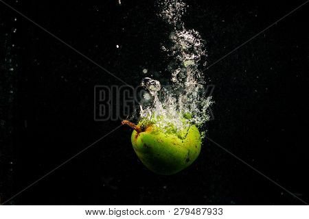 Green Pear Splashes Water Falling On Black Background