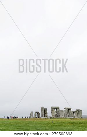 Amesbury, Great Britain - Dec 23, 2018: Tourists Watching The Stone Monument Stonehenge A Cloudy Day