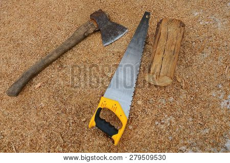 Old Ax And Hacksaw C Logs Lie On Brown Sawdust On The Street