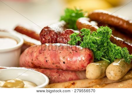 Dish With Different Kinds Of Sausages. Different Kinds Of Sausages With Parsley And Pot Of Mustard.