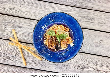 Dish With Mussles And Finely Chopped Cheese Top View. Blue Plate Of Dish With Pasta, Cheese, Mussles
