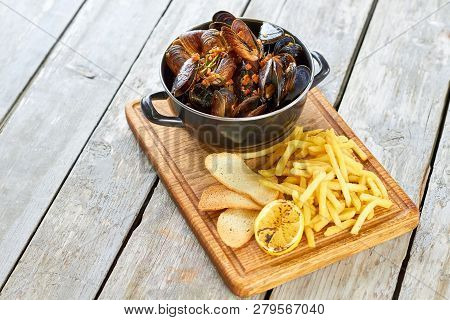 Belgian Mussels In White Wine With Tomatoes, Croutons And French Fries. Fried Food, Pile Of Shell Mu