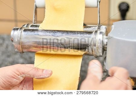 Male Hands Are Rolling A Dough On A Roller Machine. Chef Making Dough For Pastry On Dough Sheeter.