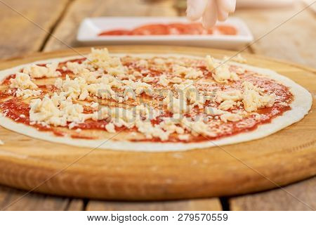 Close Up Pizza Basis Sprinkled With Cheese. Red Sauce With Shredded Cheese On Pizza Crust.