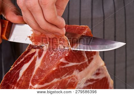 Prosciutto Or Jamon Serrano. Close Up On Hands Of A Chef Cutting Traditional Italian Spanish Ham. Sl