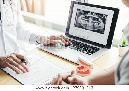 Dentist Talking To Male Patient And Presenting Results On Dental X-ray Film About The Problem Of The