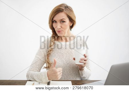 Elegant Good Looking Cheerful Senior Woman In White Sweater Holding Papercup With Hot Tea Or Coffee,