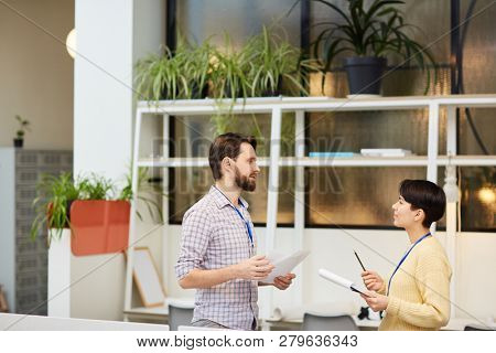 Two young economists with financial documets discussing their ideas about forecasting situation on stock market