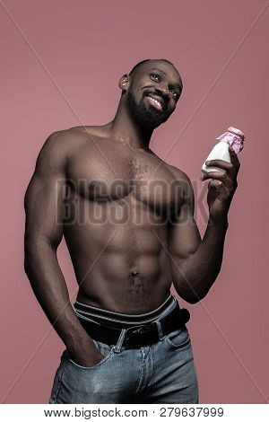 Healthy Young African Man Holging Little Bottle Of Milk On A Pink Studio Background. Close Up Portra
