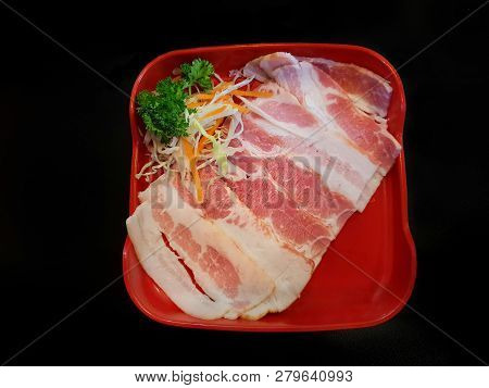Top View Of Raw Bacon With Carot And Cabbage In Red Dish Isolated On Black Background In Restaurant 