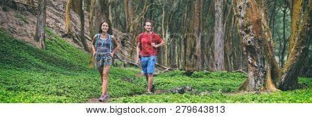Hiking couple tourists walking in forest panoramic lansdcape banner. Travel background vacation nature rainforest landscape, happy hikers people with backpacks.