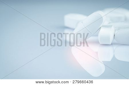 Pile Of White Oblong Tablets Pills On Gray Background. Pharmaceutical Industry. Pharmacy Products. P