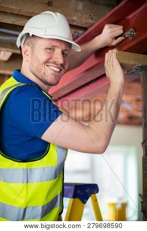 Construction Worker Fitting Steel Support Beam Into Renovated House Ceiling